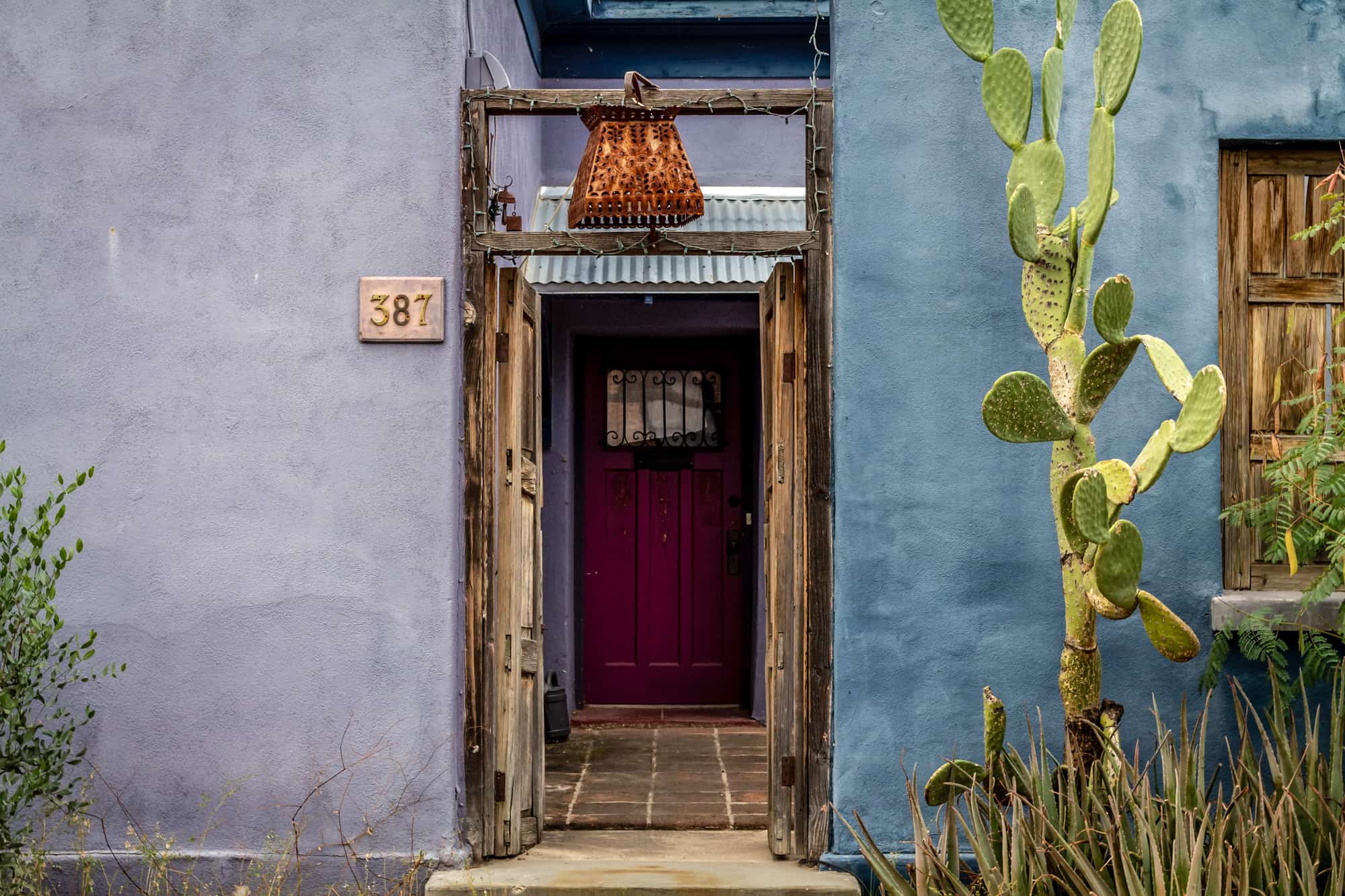 a doorway with colorful purple and blue painted adobe walls and red door, seeing these gorgeous homes downtown is part of our tucson itinerary