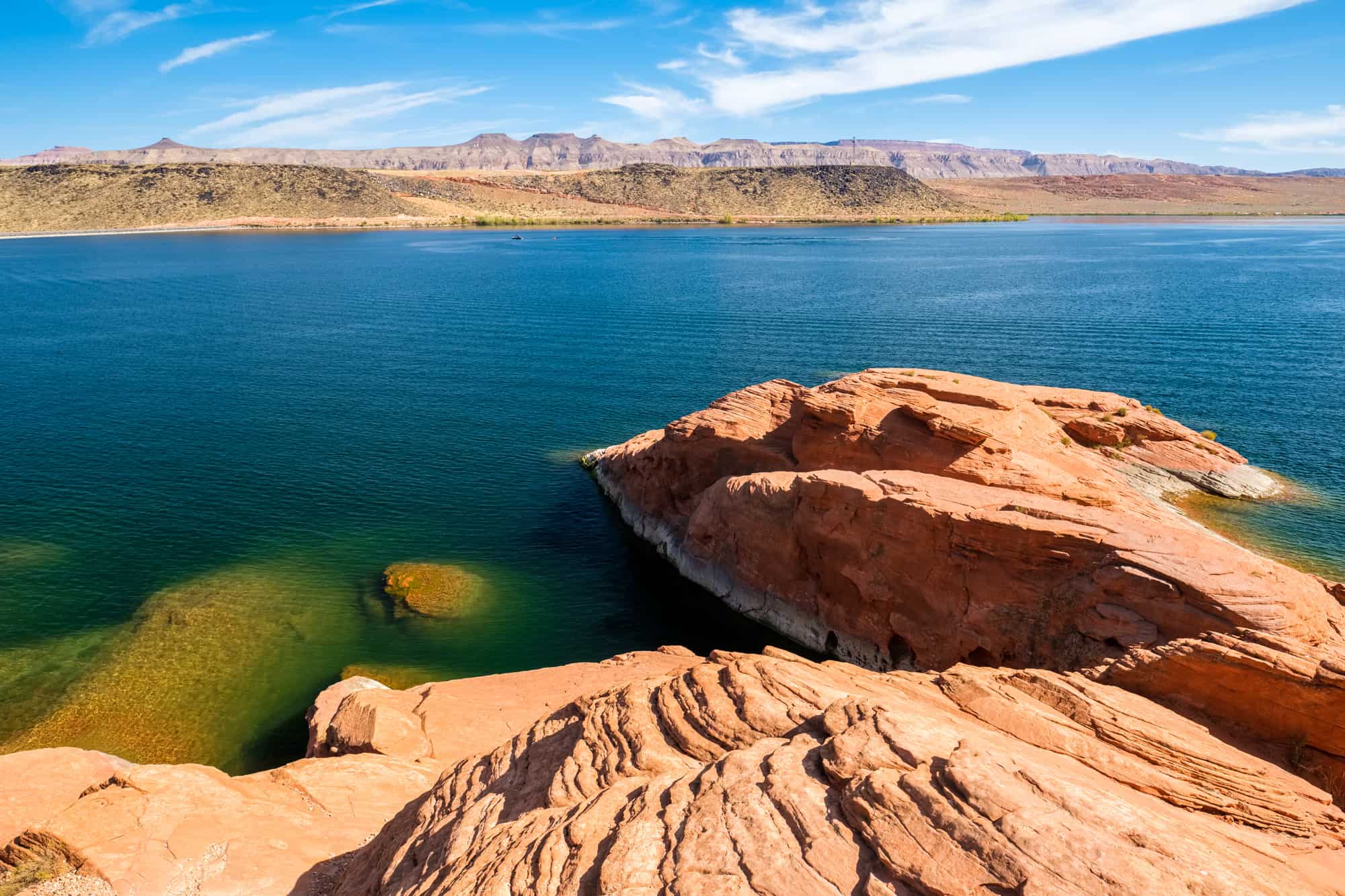 the sand hollow state park consists of a huge lake offering plenty of water activities, photo shows the lake with red rocks along the shoreline