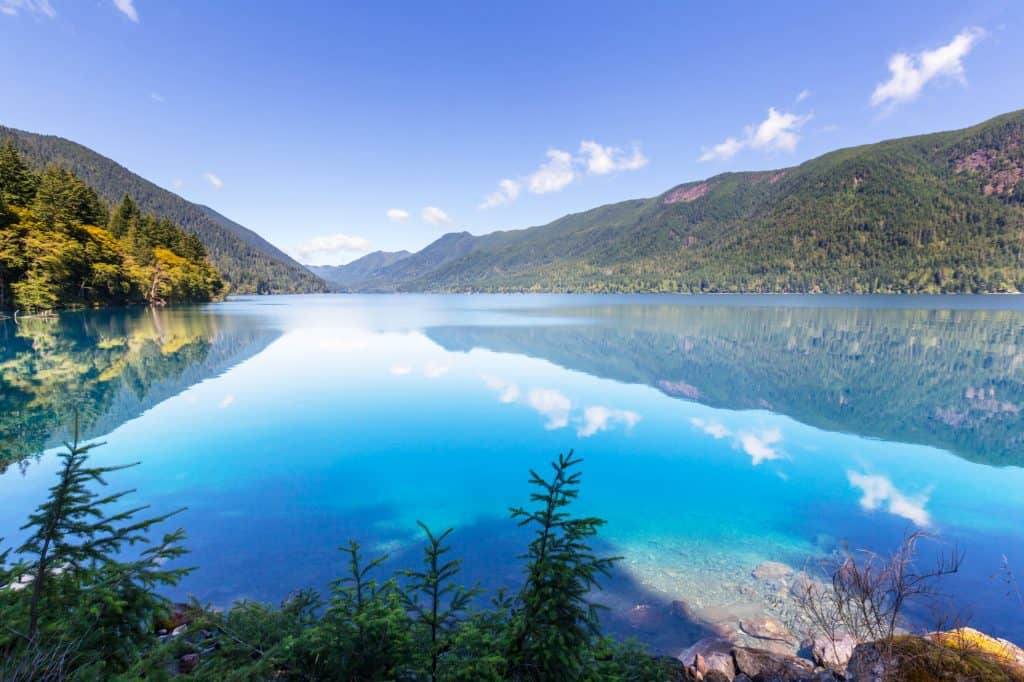 the aqua blue crescent lake surrounded by treed mountains and a blue sky