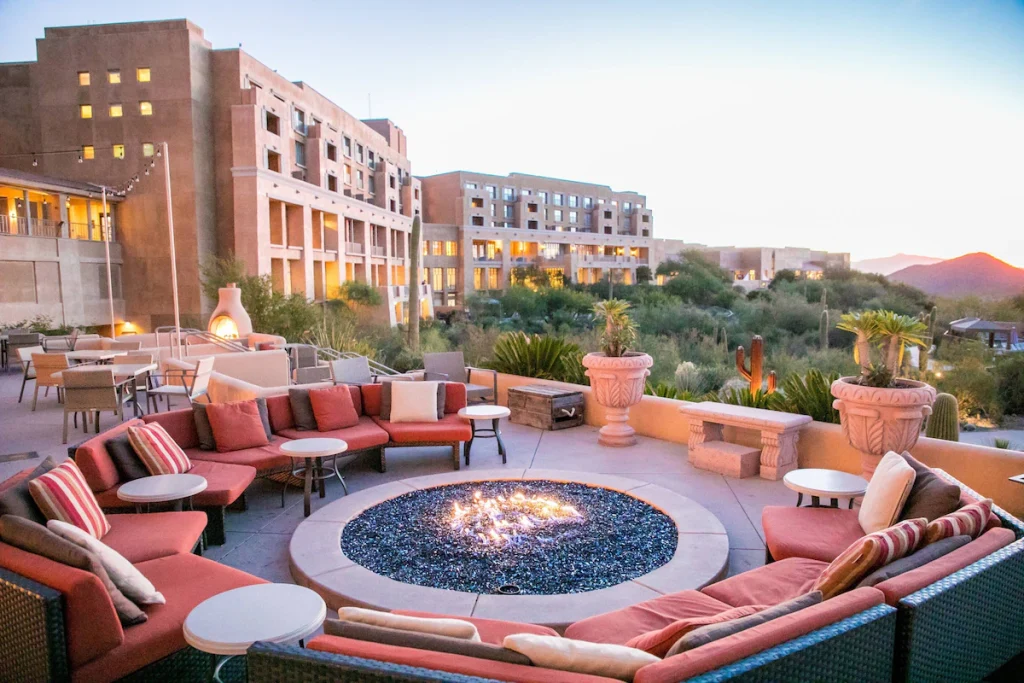 a firepit at the lovely JW Marriott, with orange cushy suits in a circle around the fire with the hotel in the background