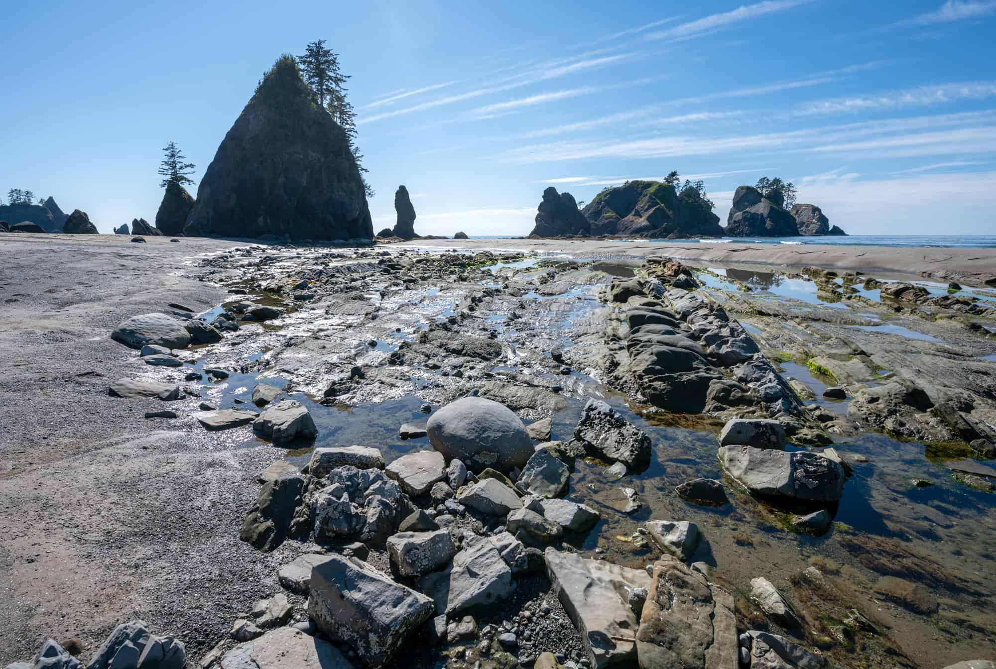 shi shi beach at low tide undercovers rocks and tide pools, sea stacks can be seen in the background under a blue sky