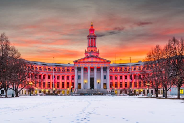 the denver city and county municipal building at sunset in winter with snow on the ground and beautiful pink light on the building and in the sky above