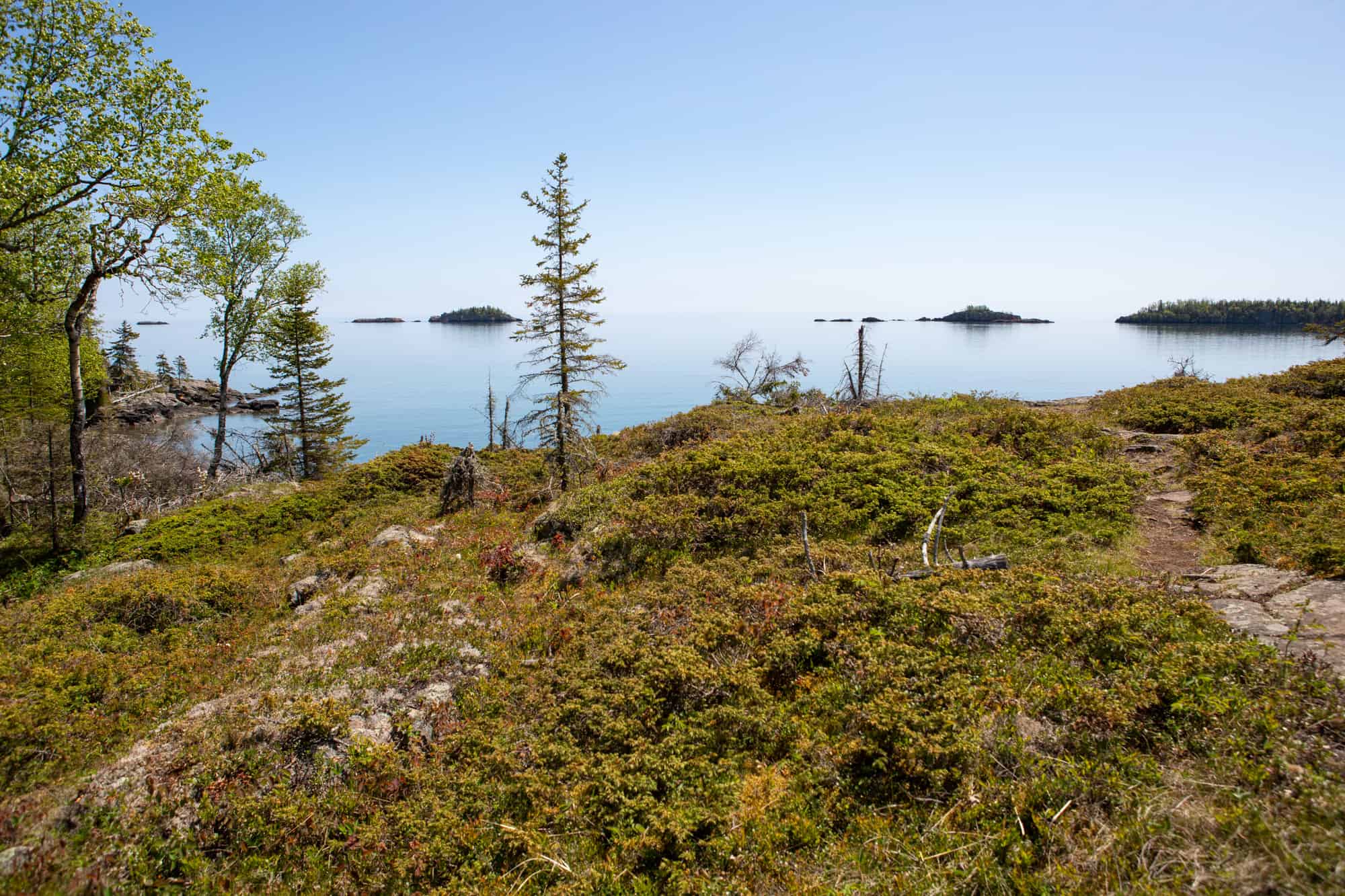 a view from the shore of isle royale national park, with some small rocky islands off shore in the sunshine