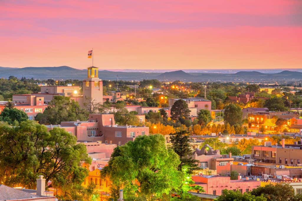 santa fe new mexico at sunset with pink and purple hues above a skyline of buildings and churches