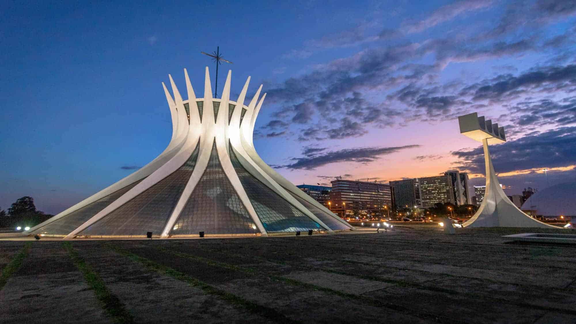 The modern and unique architecture of the Cathedral of Brasília in Brazil, captured at sunset, with its white, crown-like structure standing out against the twilight sky.