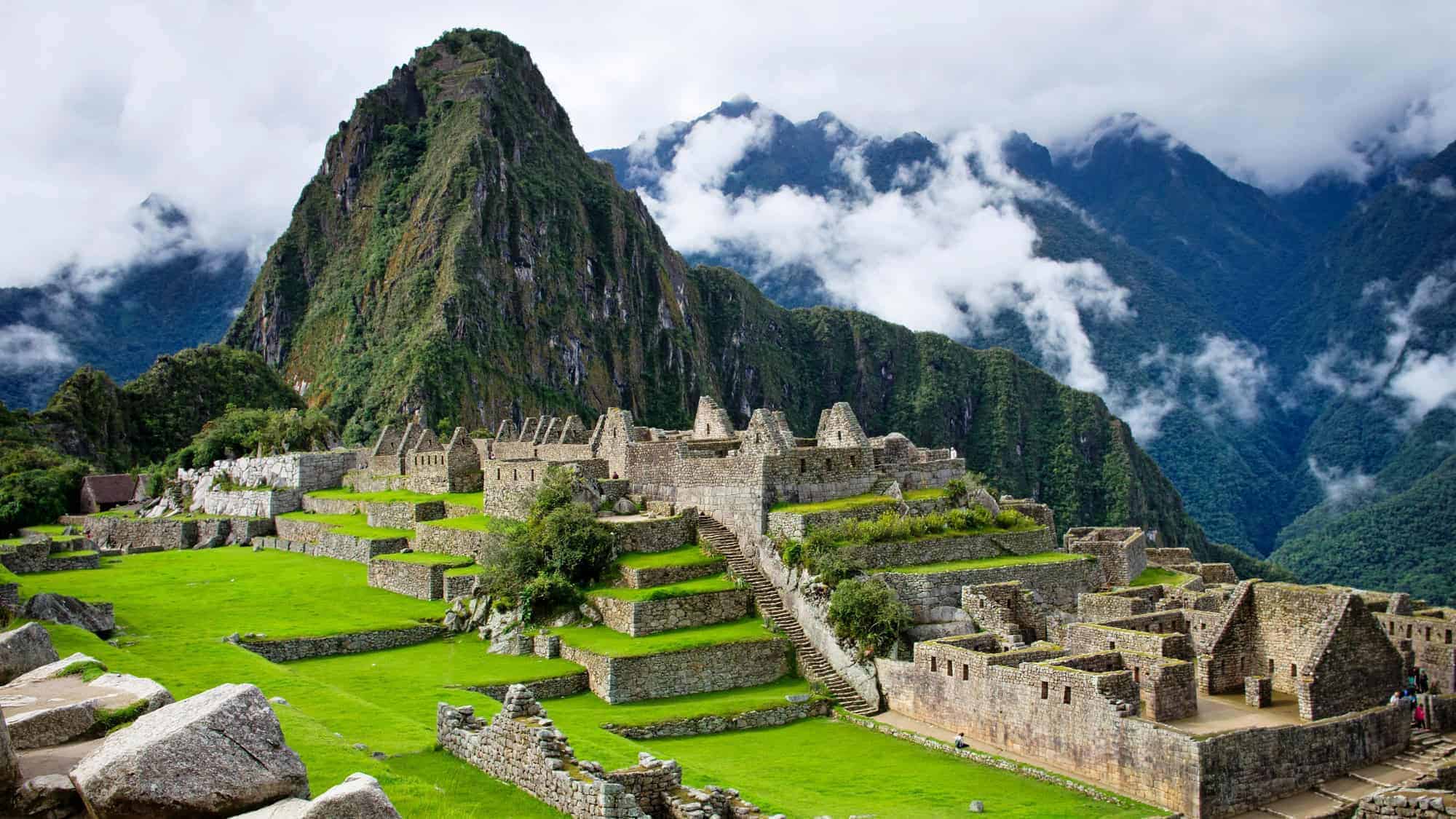 A breathtaking view of Machu Picchu, an ancient Incan city nestled high in the Andes Mountains of Peru, surrounded by lush greenery and misty peaks.