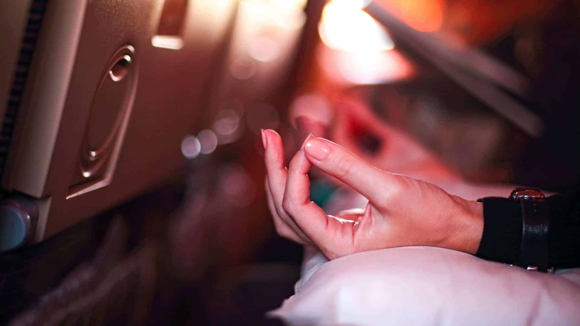 Hands in a meditation pose, resting on an airplane tray table.