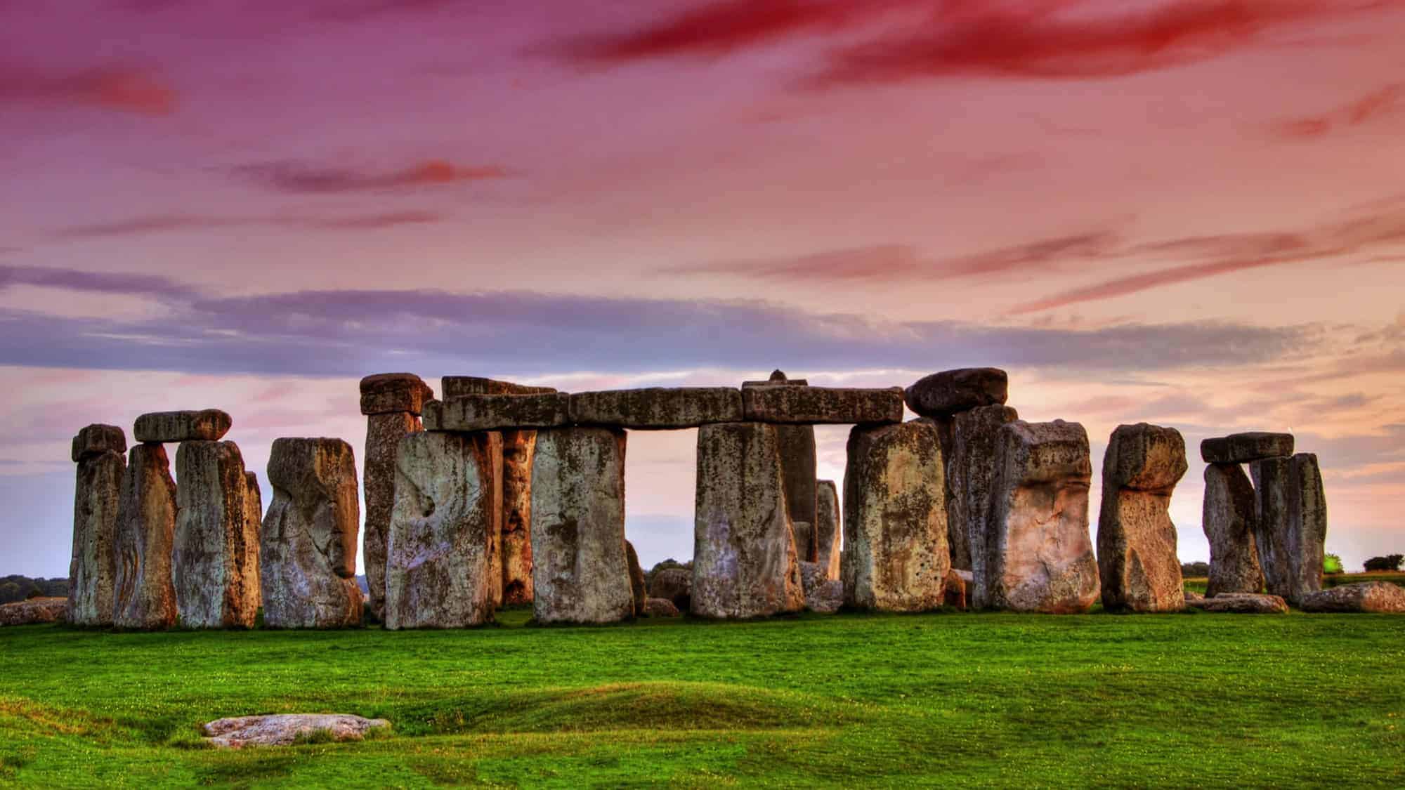 Stonehenge at sunset, featuring its famous prehistoric stone circle set against a colorful sky.