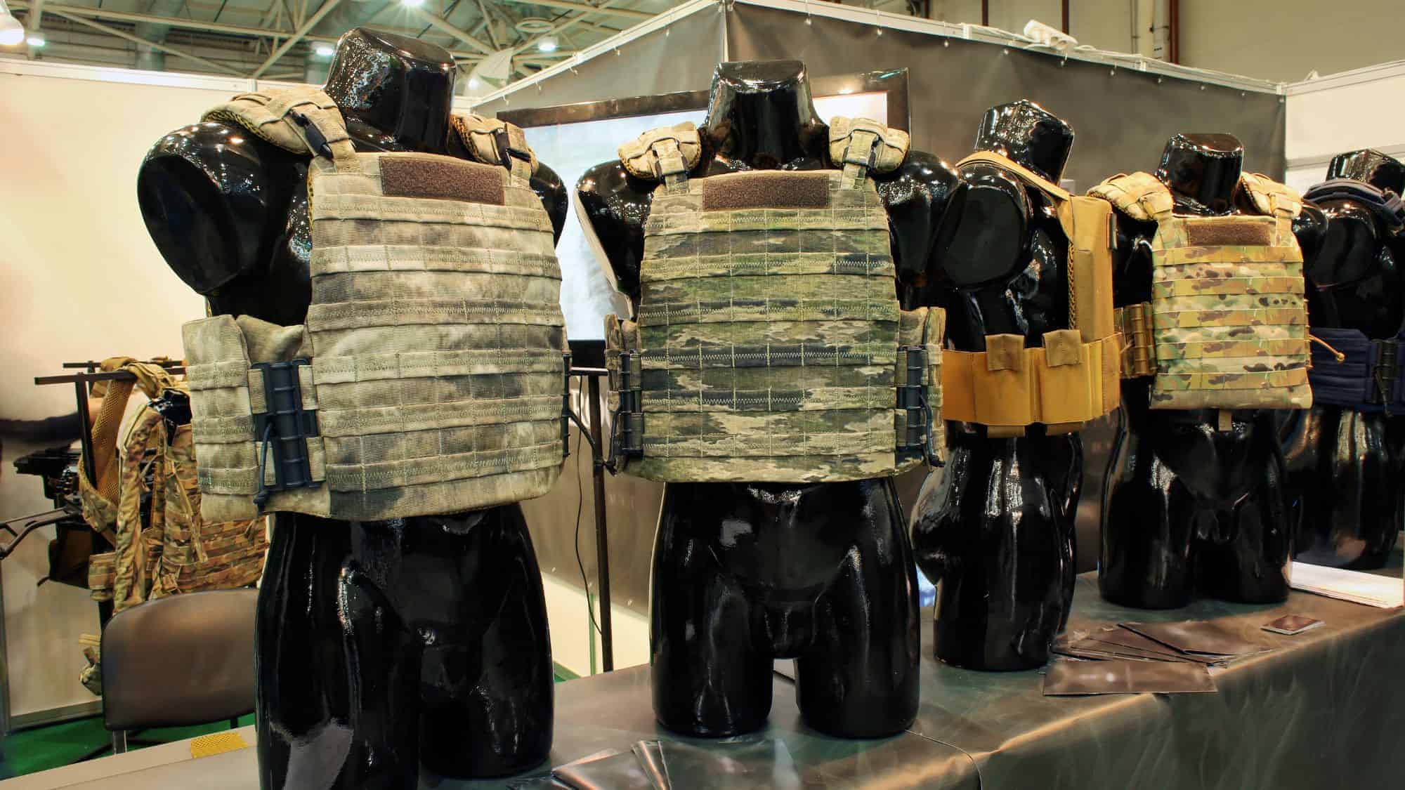 A hand reaching down to pick up seaweed from the sand on a beach, with soft ocean waves blurred in the background.
