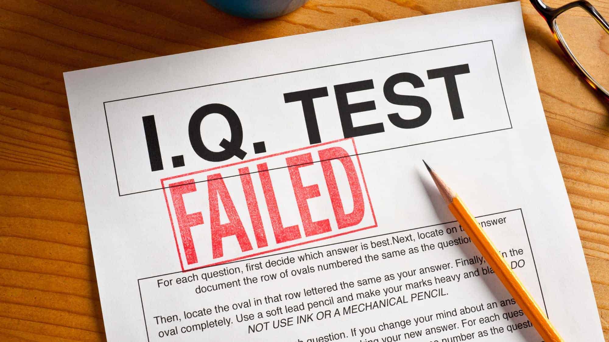 A close-up of a test paper with the bold text "I.Q. Test" and a large red "FAILED" stamp over it, with a pencil resting on the paper.