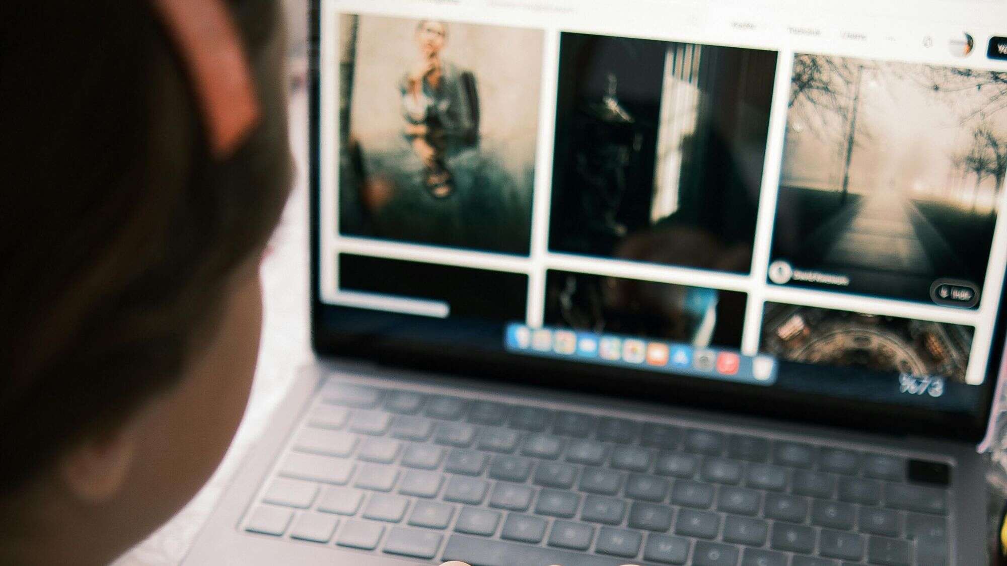 A man sits facing toward a laptop screen full of images