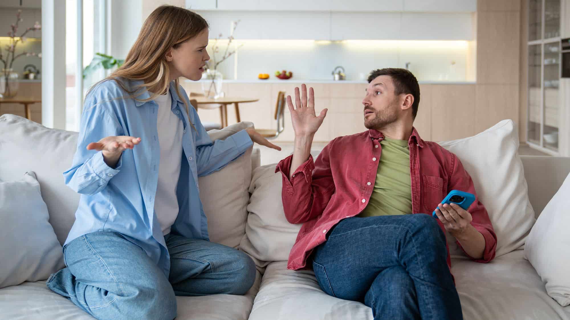 A woman and man argue while sitting on the couch.
