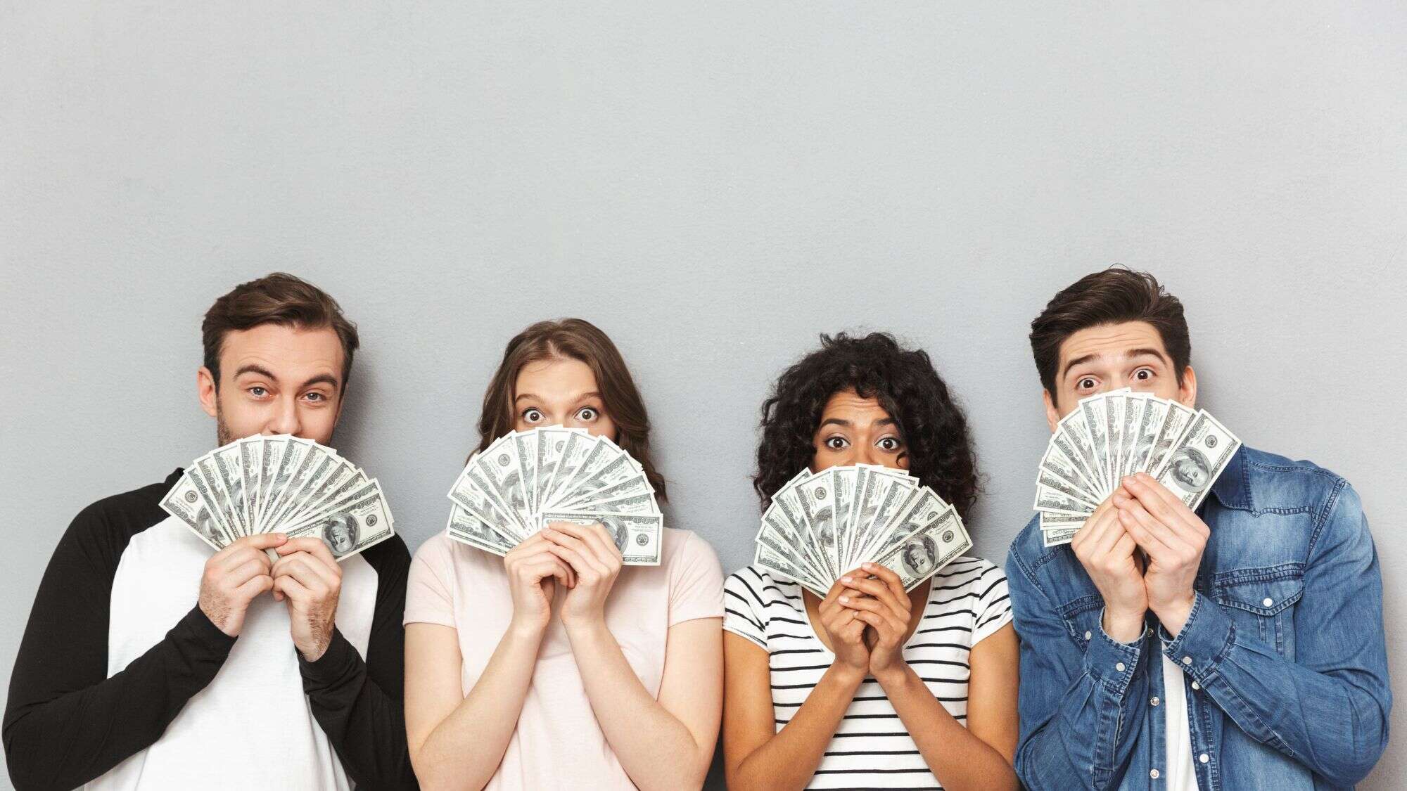 a group of people holding a fan of cash under their faces