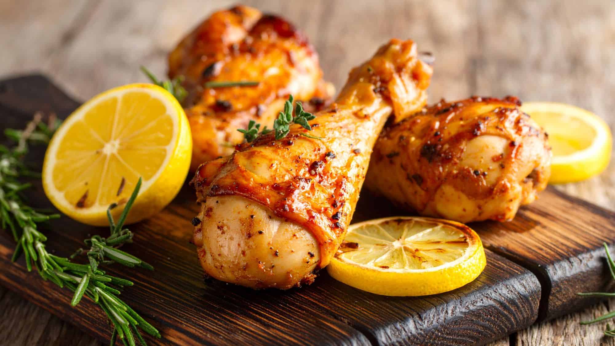 Golden-brown lemon herb roasted chicken, garnished with fresh parsley and capers. Slices of lemon add a bright contrast to the dish.