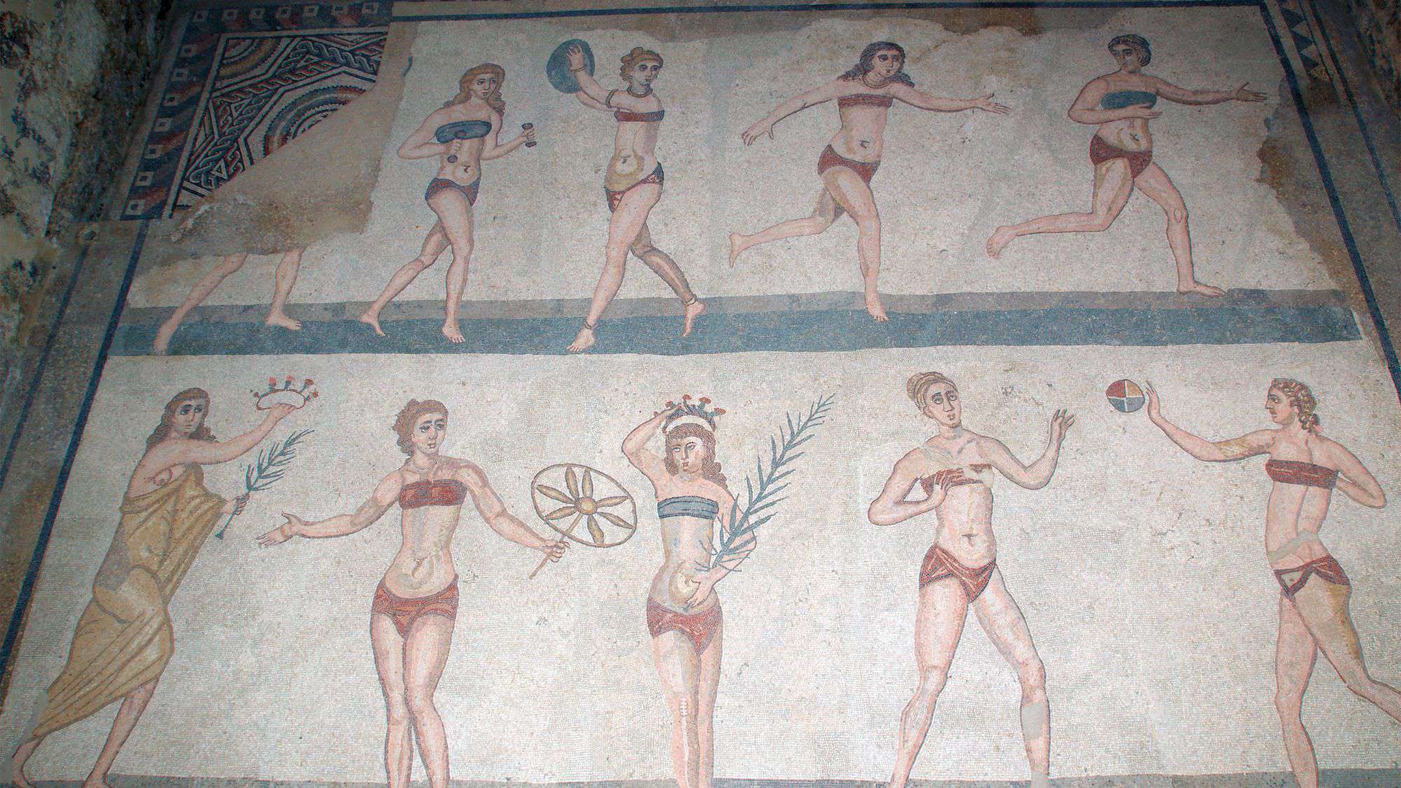 Ancient Roman mosaics from the Villa Romana del Casale, depicting athletic women, often called "Bikini Girls," engaged in sports and leisure activities. The detailed artwork highlights the villa's historical and artistic significance.