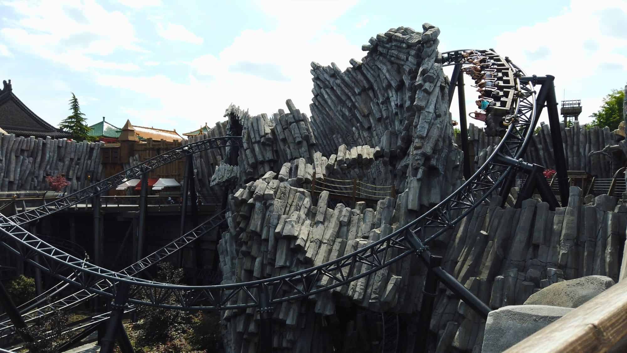 A thrilling steel roller coaster twisting through artificial rocky peaks at Phantasialand in Germany, giving an adventurous and rugged landscape.