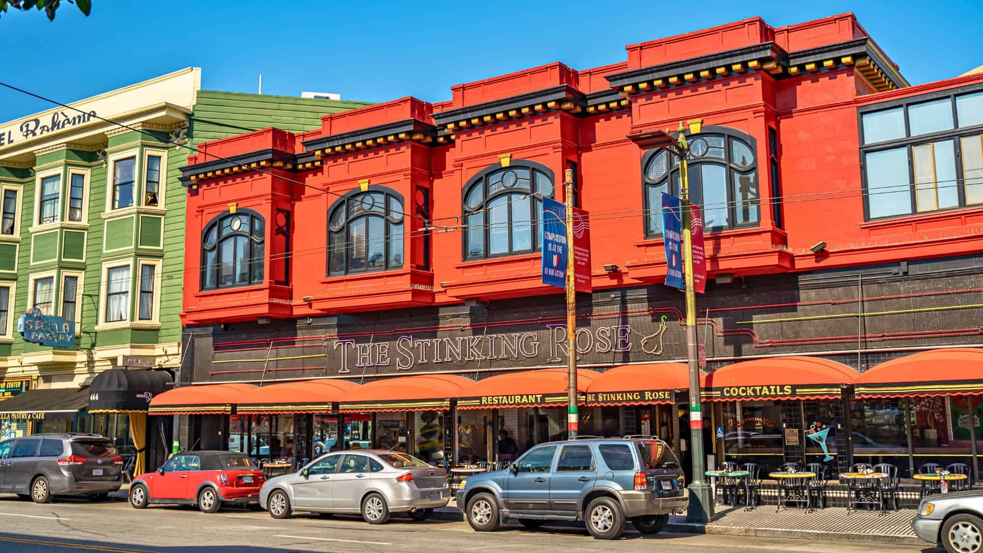 A bold red and black restaurant exterior in San Francisco's North Beach, famous for its garlic-infused dishes, with large signage and sidewalk seating.
