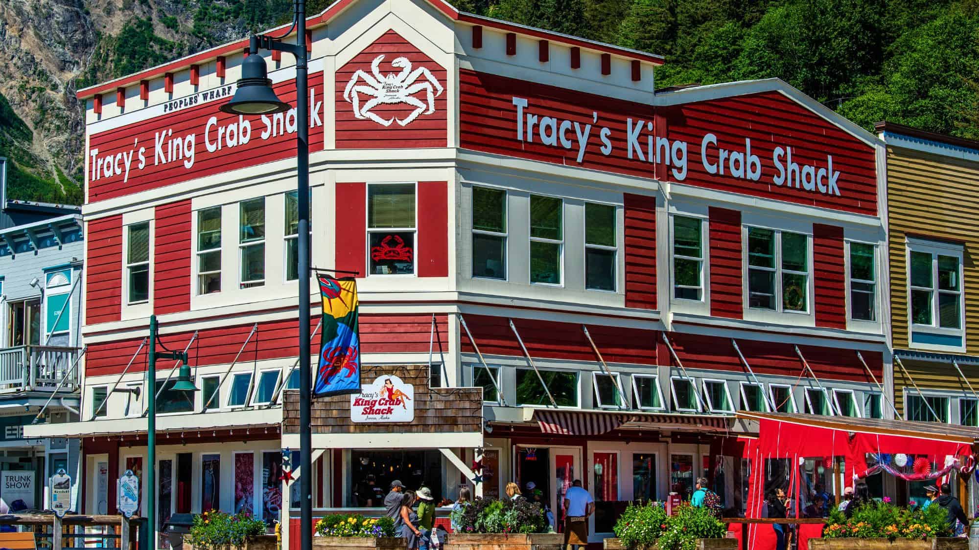A two-story red and white building in Juneau, Alaska, with bold signage and a large crab logo, surrounded by tourists and colorful banners.