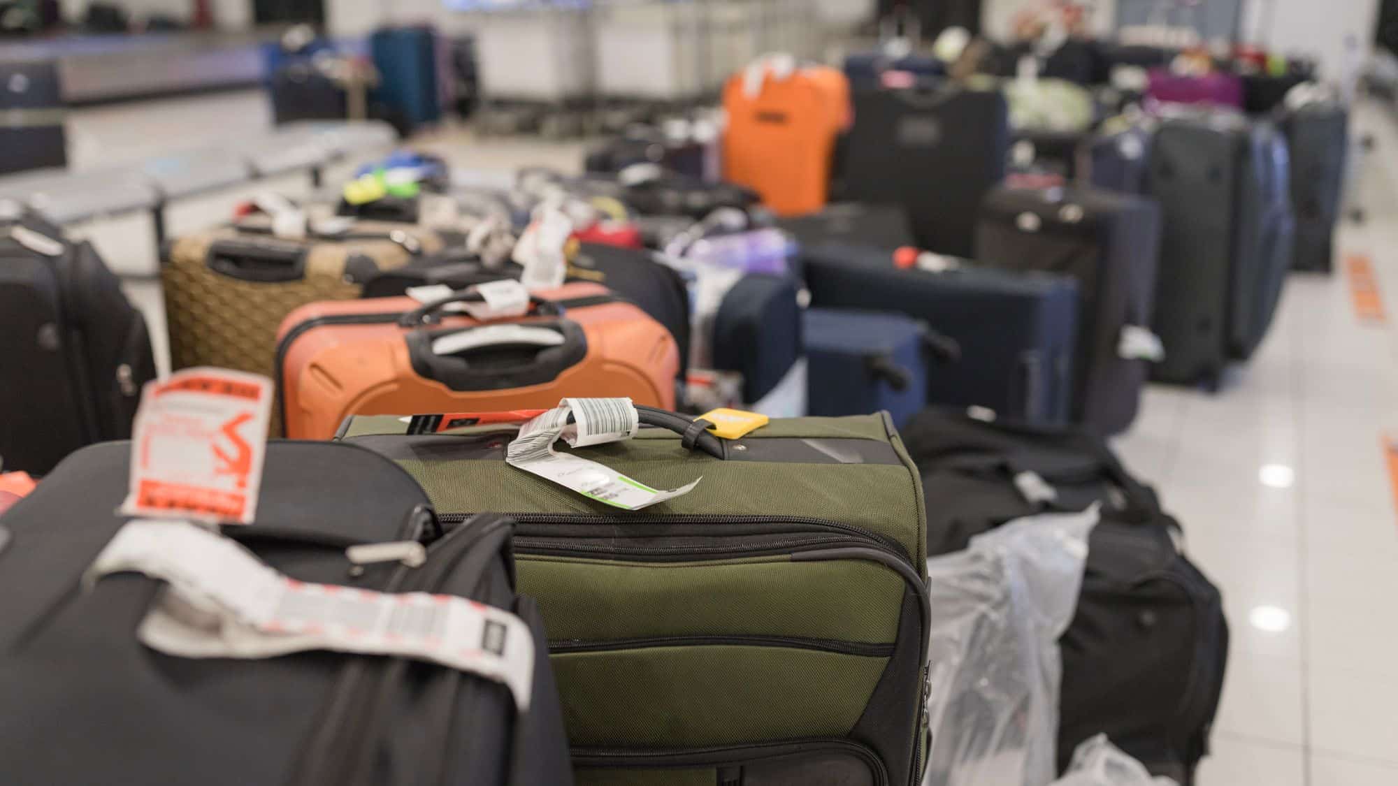 A pile of suitcases with destinations tags in an airport.