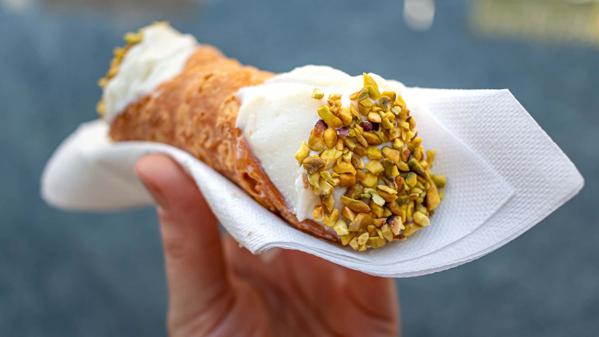 Close up of a fresh Italian Cannoli, held by hand