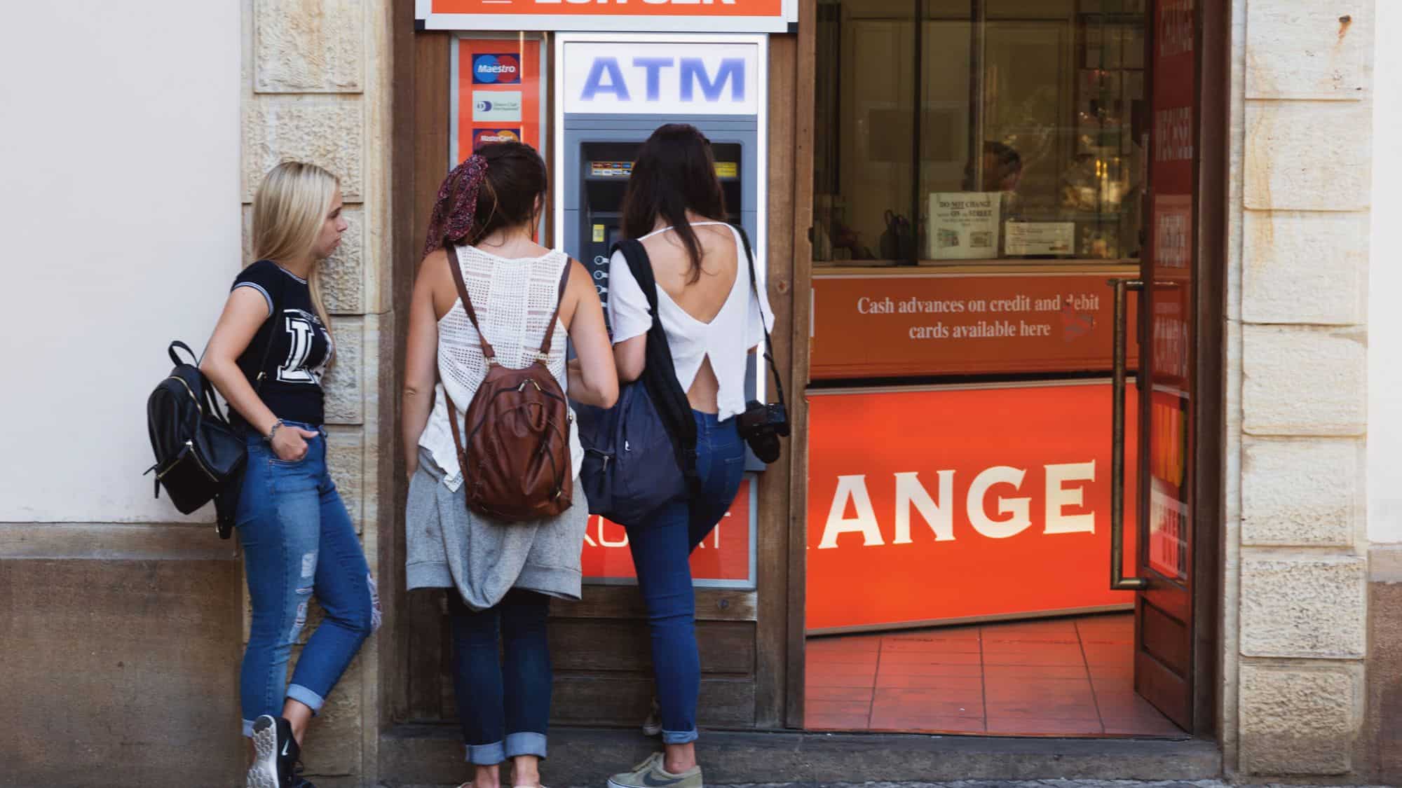 Prague, Czechia - Jul, 2, 2018: Three young women and ATM. Three young beautiful modern women using an automated teller machine. Girls withdrawing money or exchanging money.