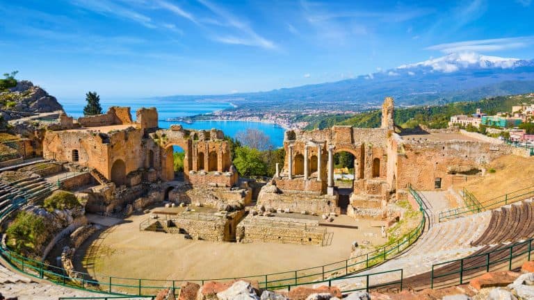 Ruins of Ancient Greek theatre in Taormina on background of Etna Volcano, Italy. Taormina located in Metropolitan City of Messina, on east coast of island of Sicily.