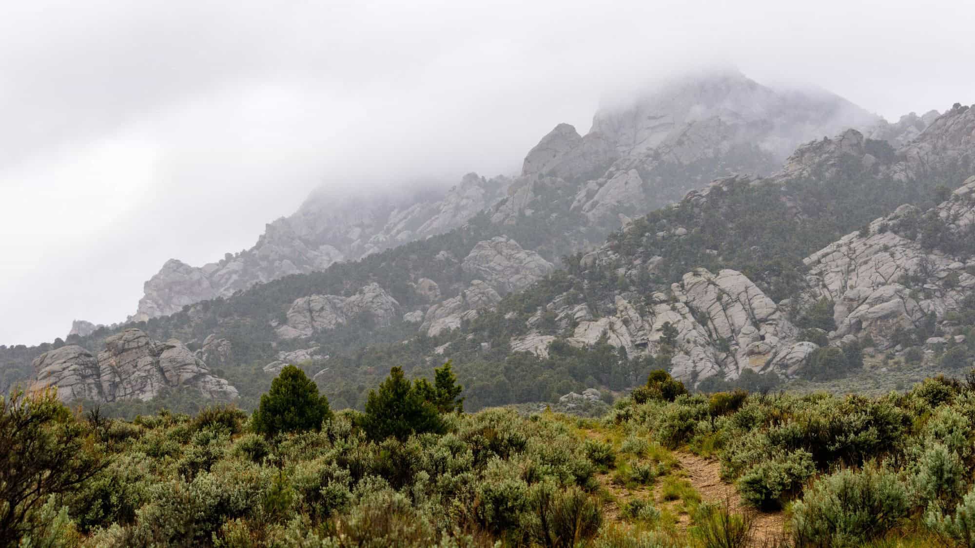 Jagged granite formations rise out of a misty sagebrush valley at City of Rocks National Reserve, a quiet and rugged expanse ideal for rock climbing and scenic hikes.