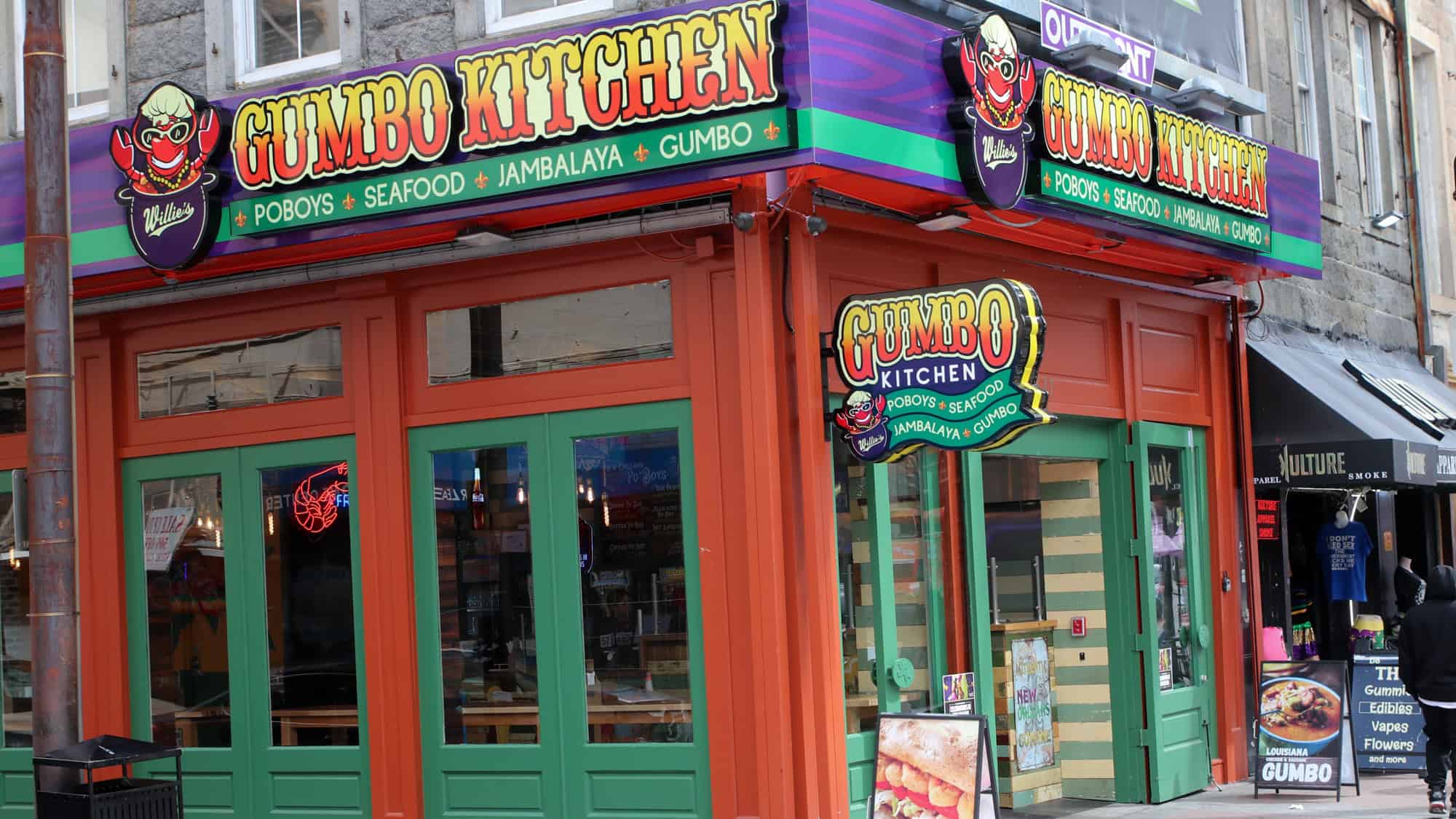 A colorful New Orleans–style restaurant front with bright signs advertising poboys, seafood, jambalaya, and gumbo.
