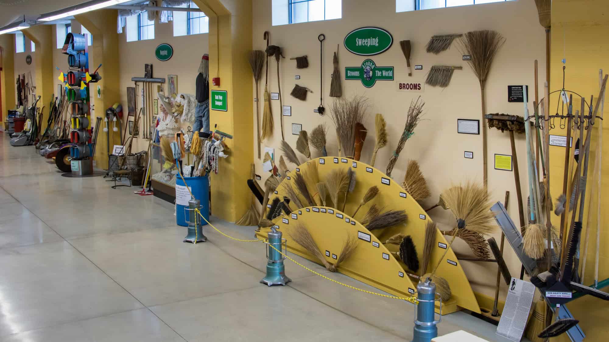 An indoor exhibit wall displays an eccentric array of cleaning tools—brooms, mops, and vacuums—from different eras at the quirky and educational Museum of Clean in Idaho.
