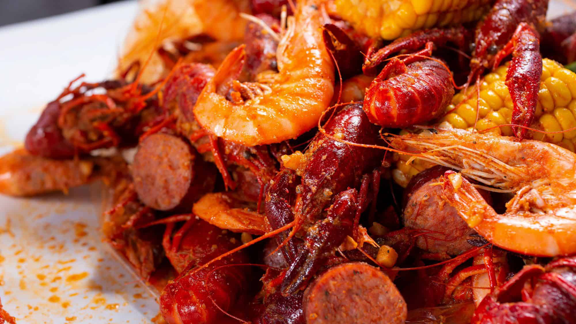 A vibrant mix of shrimp, crawfish, sausage, and corn on the cob coated in spicy seasoning.