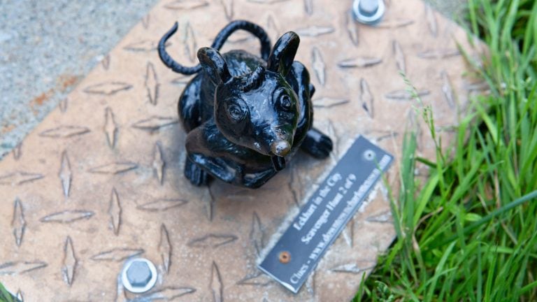 Close-up of a shiny black mouse sculpture mounted on a metal plate with a plaque that references the "Eckhart in the City" scavenger hunt in Charlottetown.