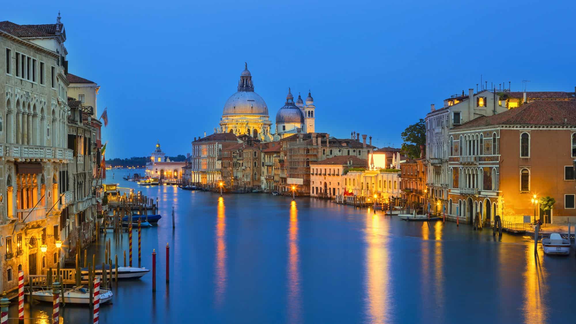 A peaceful evening view from the Ponte dell’Accademia, looking toward the domes of Santa Maria della Salute with lights reflecting on the Grand Canal.