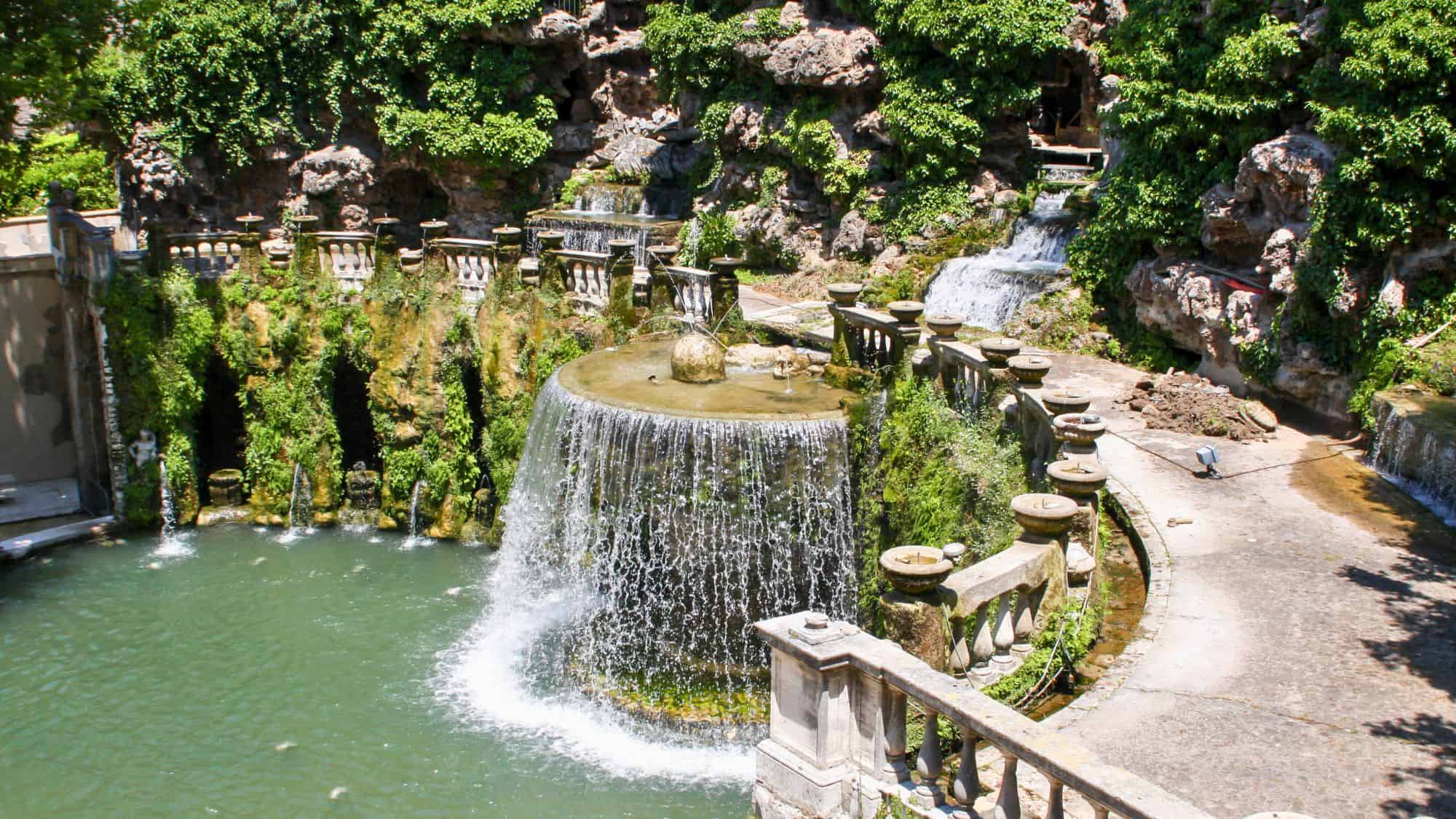 A lush Italian Renaissance garden at Villa d’Este with ornate fountains, ivy-covered stonework, and cascading water over carved balustrades.