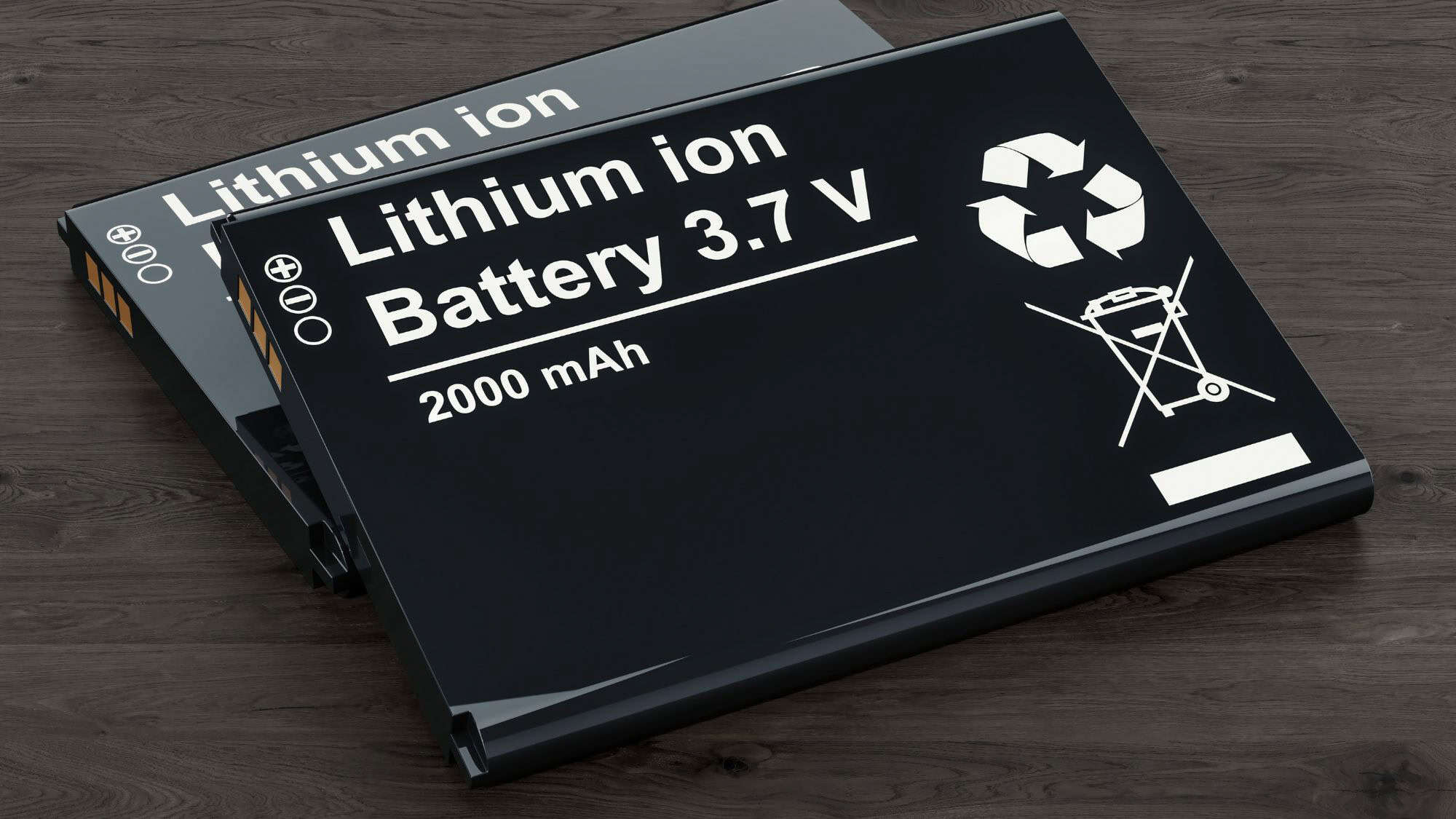 Two black lithium-ion batteries labeled "Lithium ion Battery 3.7V 2000 mAh" rest on a dark wood surface, with recycling and caution symbols prominently displayed.