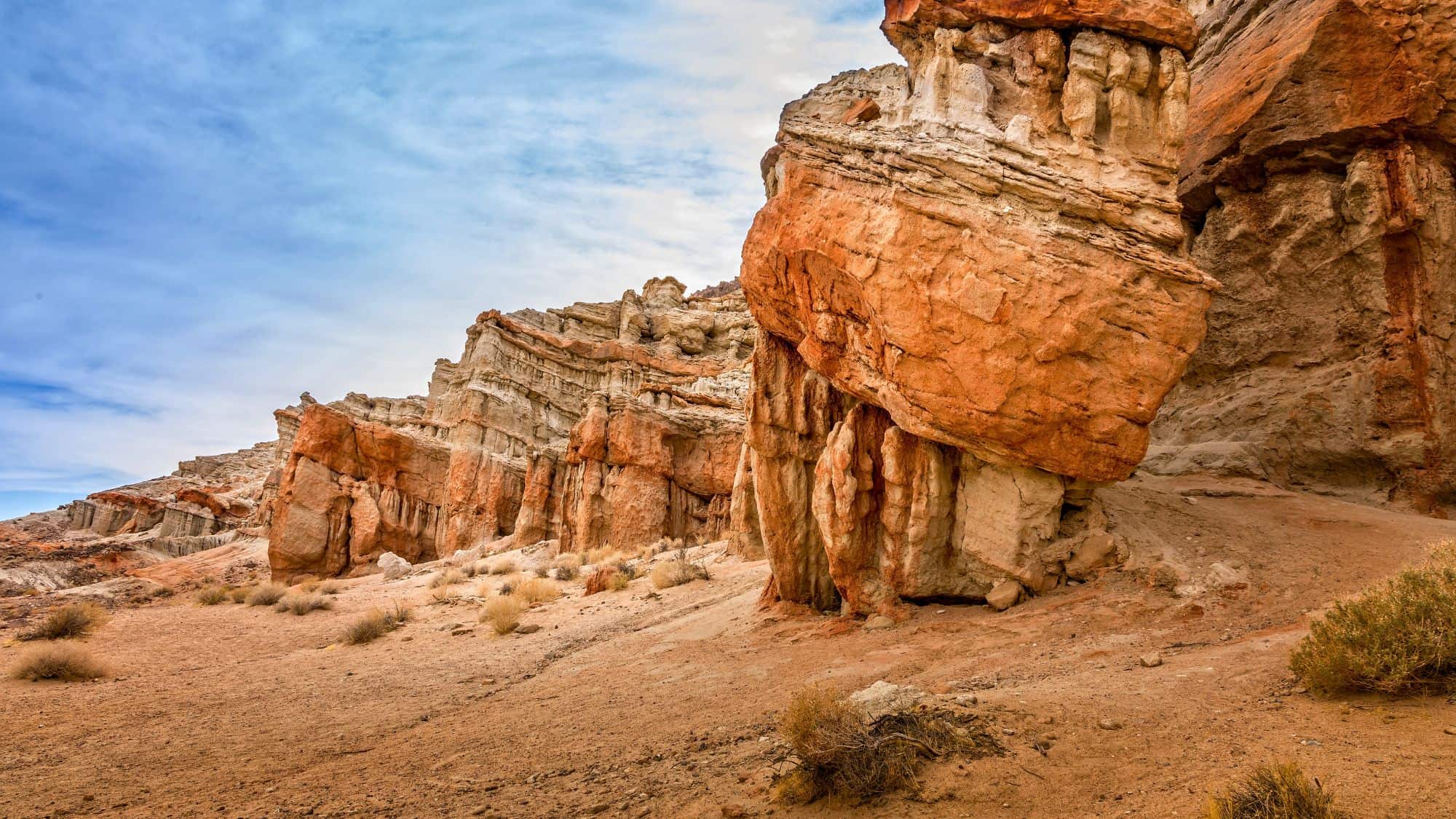Eroded sandstone cliffs in vivid reds and creams create dramatic rock formations under a blue sky at Red Rock Canyon State Park.