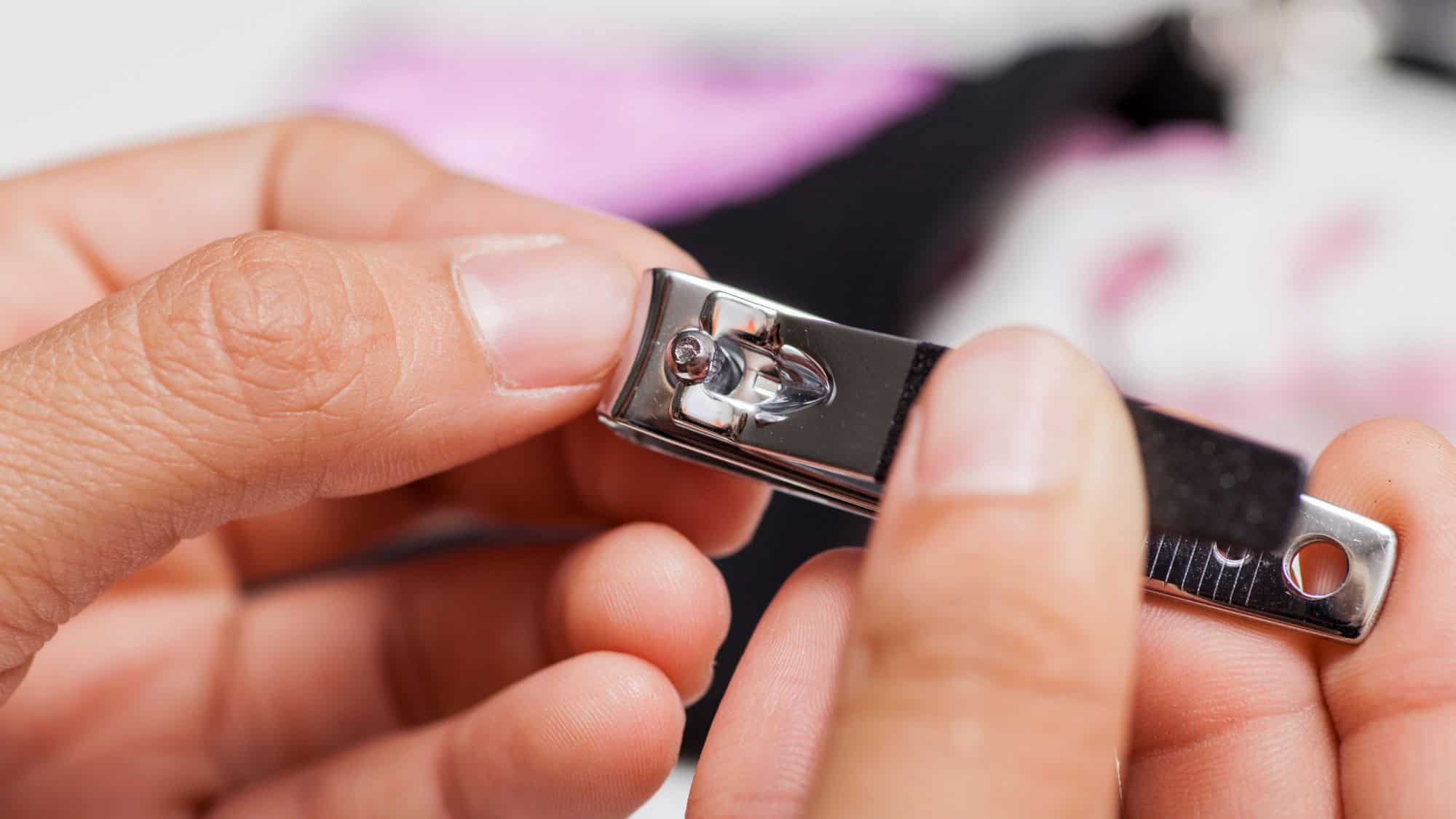 Close-up of someone clipping their fingernails mid-flight, with trimmed nails scattered on the airplane tray table—an example of poor travel etiquette.