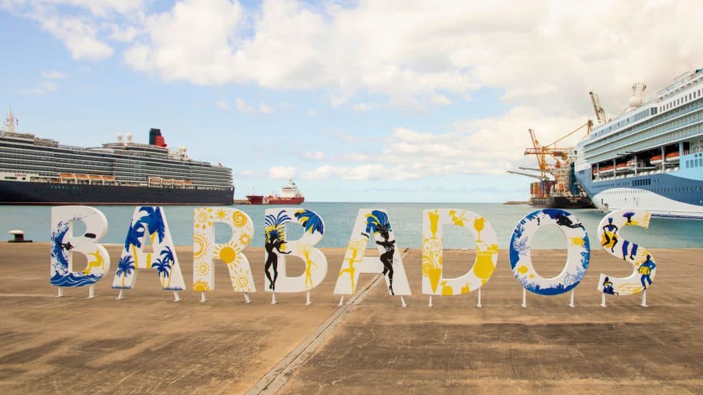 Large decorative letters spelling “Barbados” greet visitors at the port, with cruise ships and container cranes in the background.
