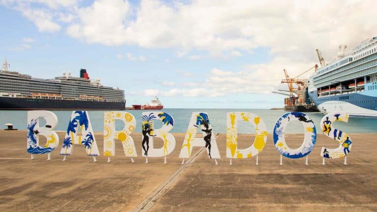 Large decorative letters spelling “Barbados” greet visitors at the port, with cruise ships and container cranes in the background.
