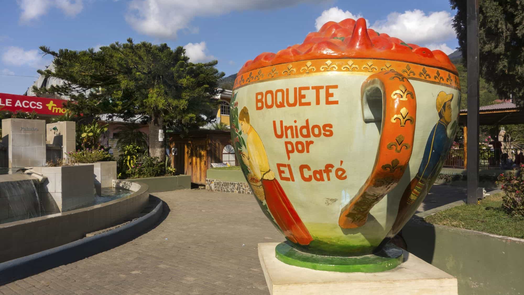 A giant decorative coffee cup in Boquete, Panama, reads "Unidos por el café" and is painted with traditional imagery, celebrating the region's rich coffee culture.