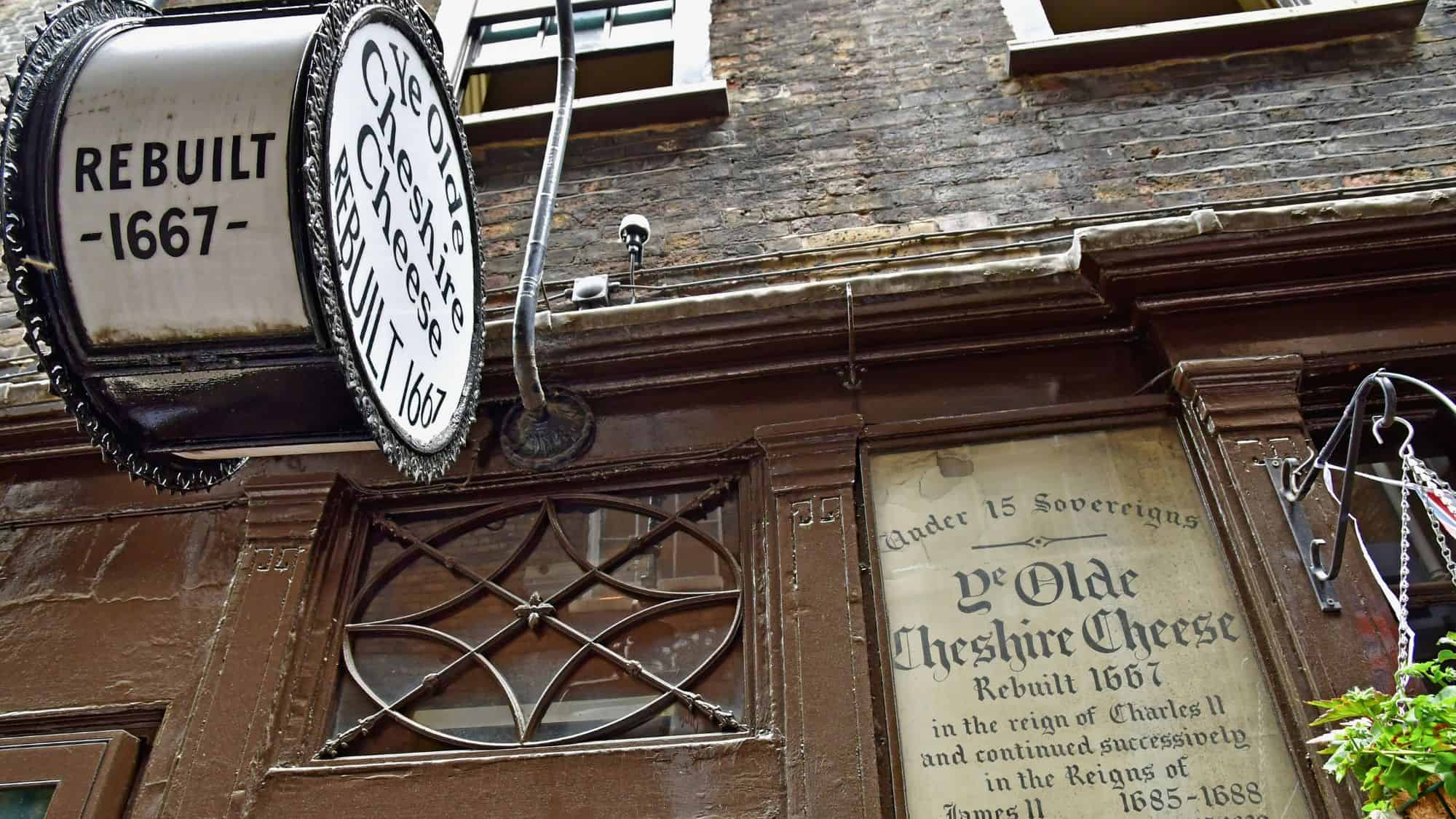 The historic façade of Ye Olde Cheshire Cheese features a hanging sign noting its 1667 rebuilding and old-style lettering on the window.