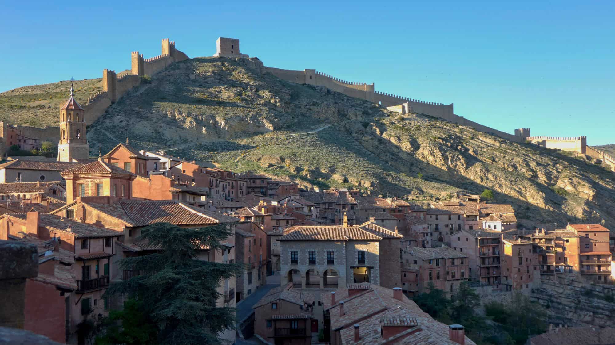 The medieval village of Albarracín is nestled at the base of a steep hillside crowned with ancient fortress walls.