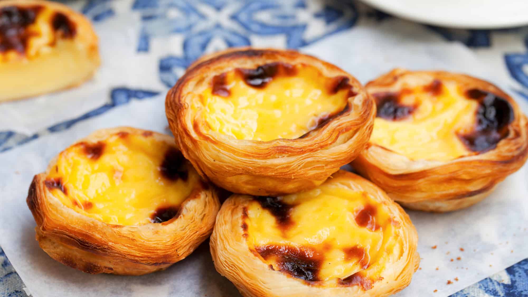 A close-up of golden, flaky pastries filled with creamy custard and caramelized tops.