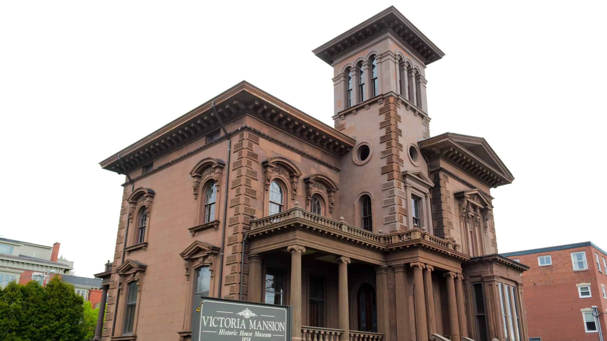 The ornate brownstone Victoria Mansion in Portland, Maine, stands tall with intricate architectural details and a central tower.