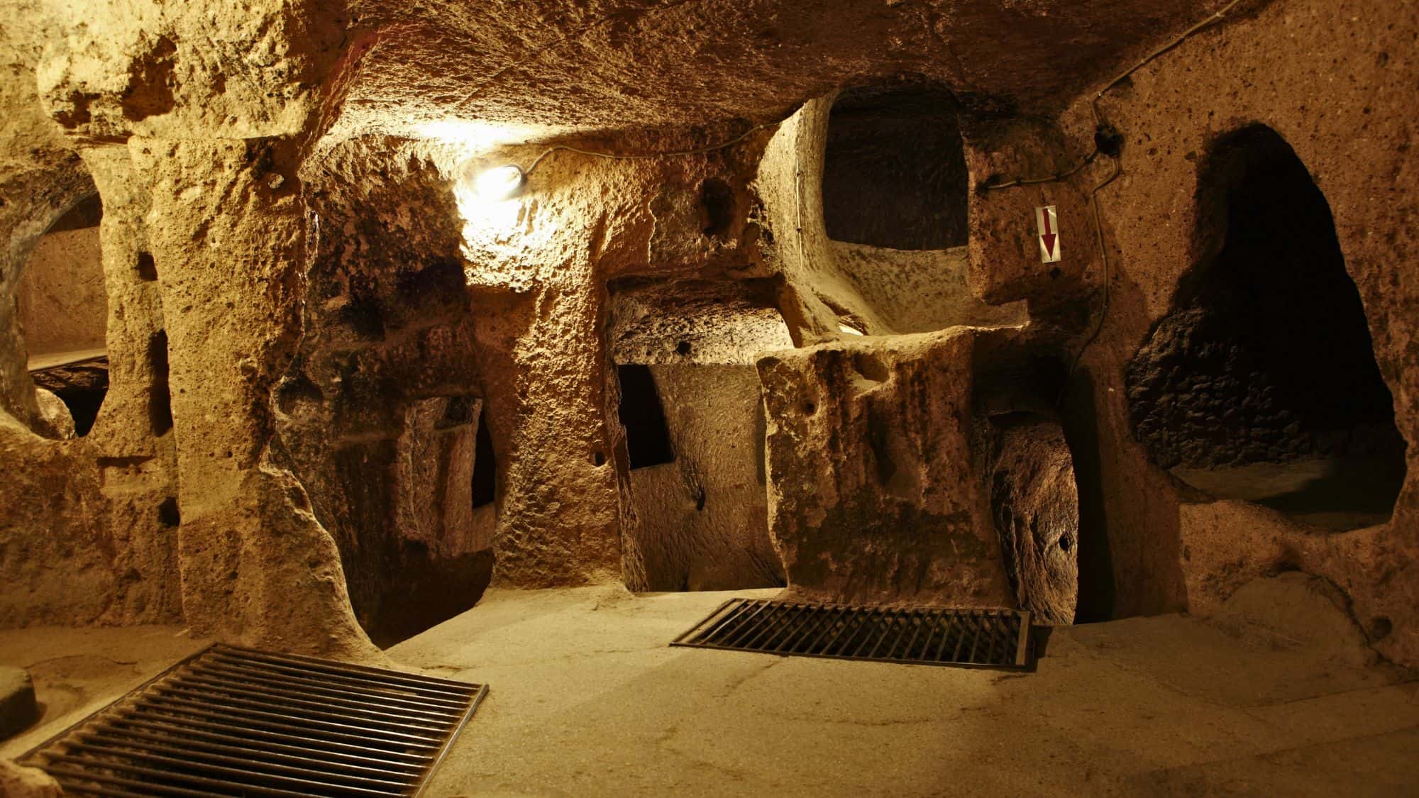 Dimly lit, carved stone chambers and narrow passages make up the ancient Derinkuyu underground city in Turkey, with ventilation shafts and hollowed walls.