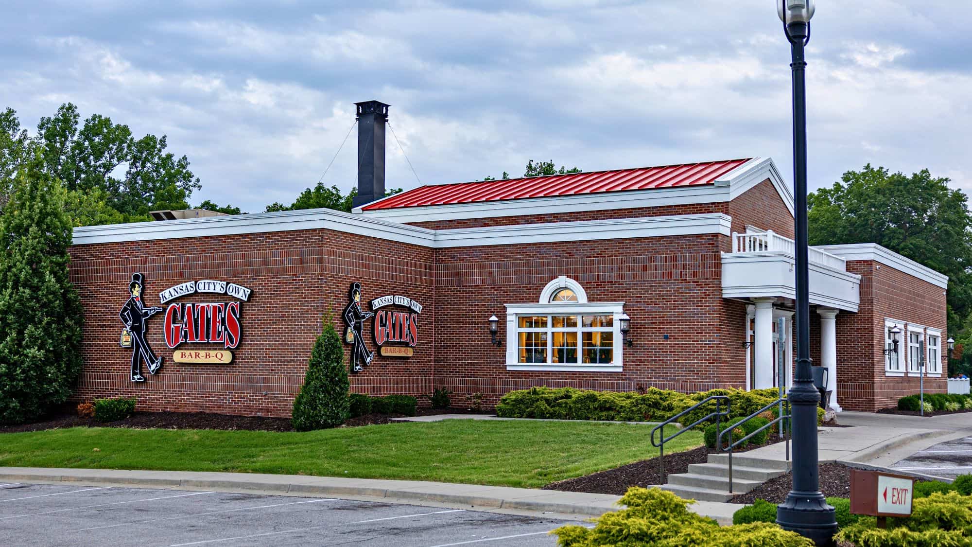 A red-brick building with a red roof displays the “Gates Bar-B-Q” sign, a famous Kansas City barbecue restaurant with a well-kept lawn and clear branding.