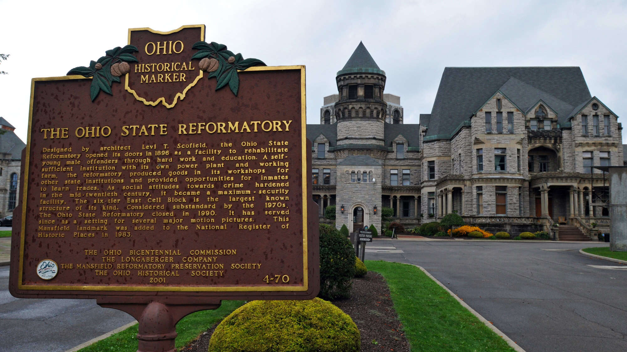 A large historical plaque in front of the Ohio State Reformatory details its architectural and penal history, with the imposing Gothic-style stone prison building in the background.