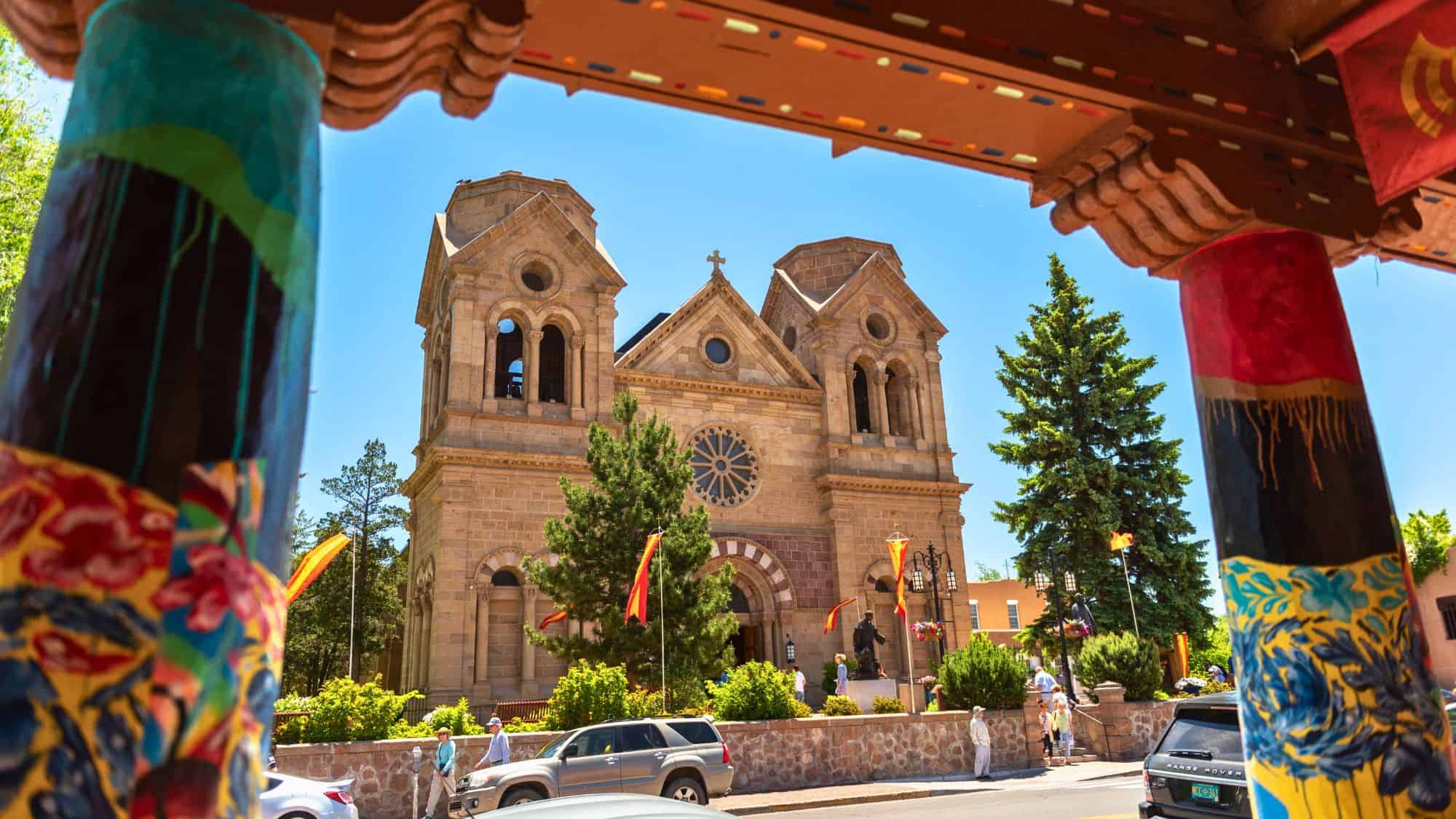Framed by colorful wooden beams, the Cathedral Basilica of St. Francis of Assisi in Santa Fe stands tall with its twin towers and Romanesque Revival façade.